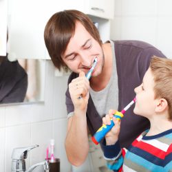 Father and son brushing teeth in bathroom