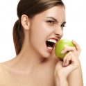 The portrait of attractive caucasian smiling woman isolated on white studio background with green apple fruits